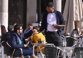 Un camarero atiende a un cliente en una terraza de la Plaza Mayor de Valladolid.