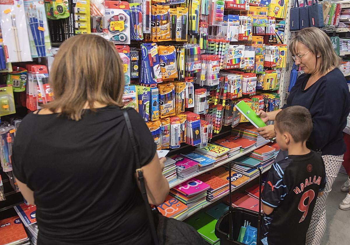 Dos mujeres y un niño acuden este viernes a una papelería de Segovia para comprar material escolar tras el primer día de colegio.