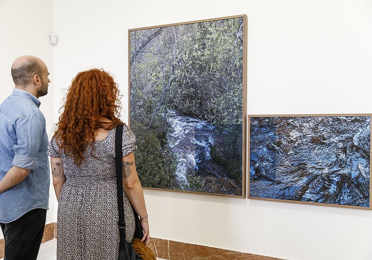 Dos personas observan algunas fotografías de la exposición.