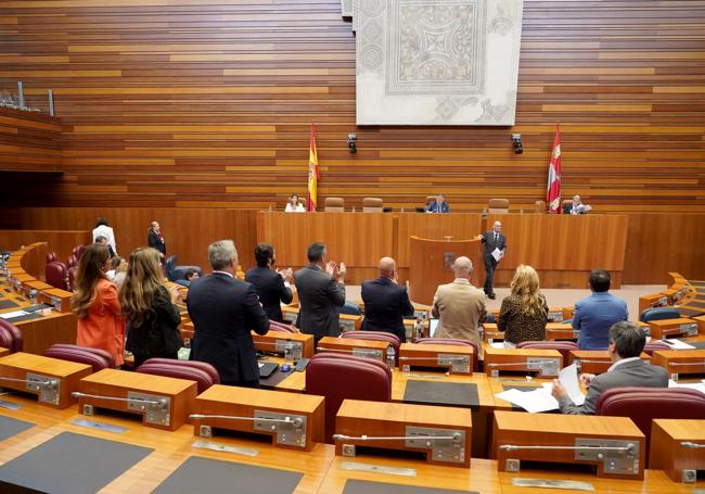 La bancada de Vox, en pie, aplaude la intervención de su procurador Javier Carrera.