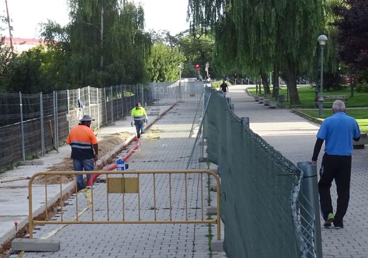 Los operarios introducen las canalizaciones para las farolas al borde de la plataforma del carril bici.