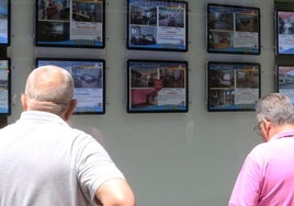 Un hombre observa varios anuncios de viviendas en venta.