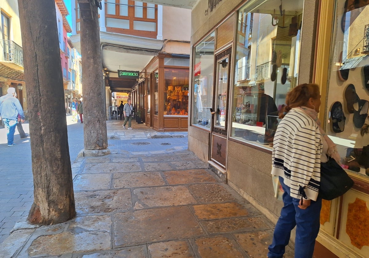 Una mujer mira un escaparate en los soportales de la comercial calle Mayor de Medina de Rioseco.