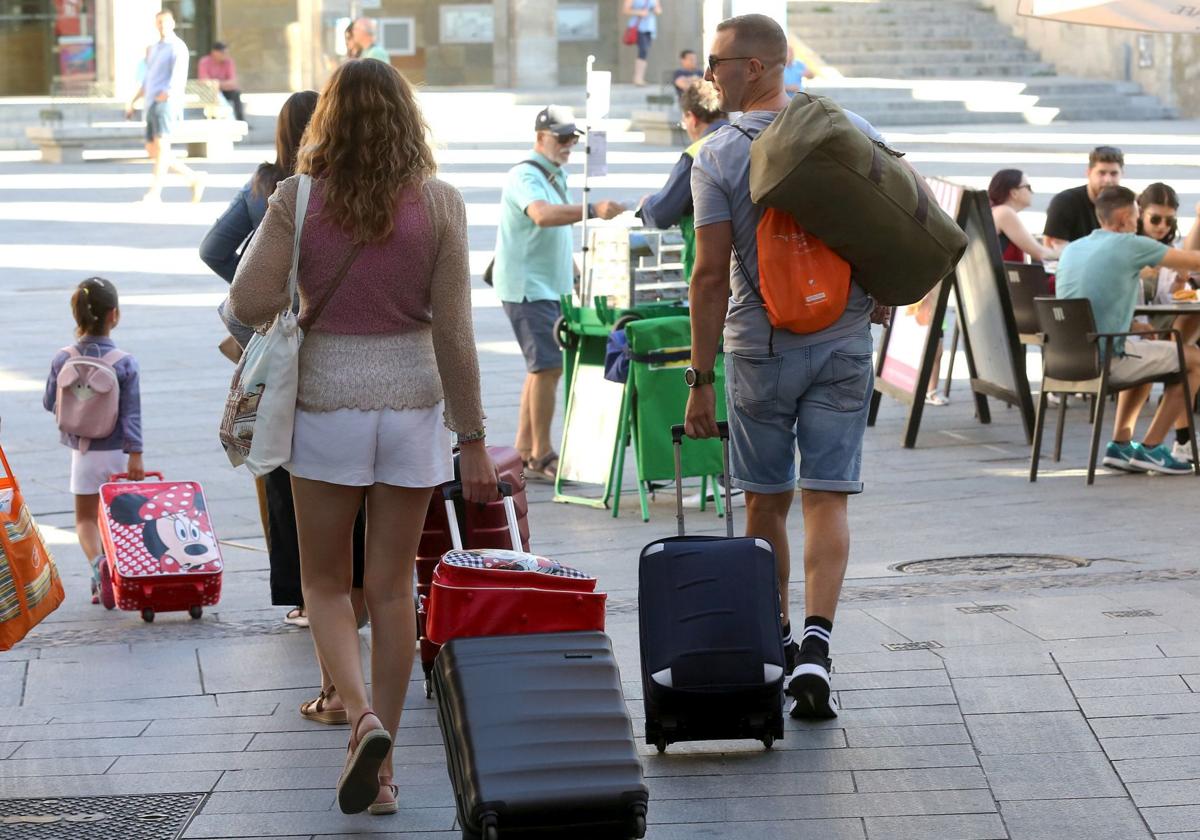 Turistas se dirigen a su establecimiento hotelero en la ciudad con sus maletas.