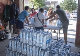 Varias personas participan en el reparto de agua en un pueblo segoviano en verano de 2023.