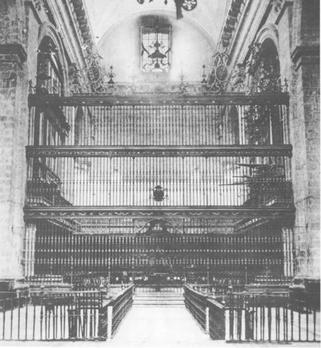 La reja del coro de la Catedral de Valladolid, en una imagen anterior a 1929. En el centro del segundo cuerpo el Cabildo colocó el escudo de armas del obispo Bustamante, en homenaje y agradecimiento a su donación. Llevaba la leyenda: «Esta reja y rallar las dio el Ilmo. Sr. Don Isidro Cosío, obispo que fue de esta ciudad».