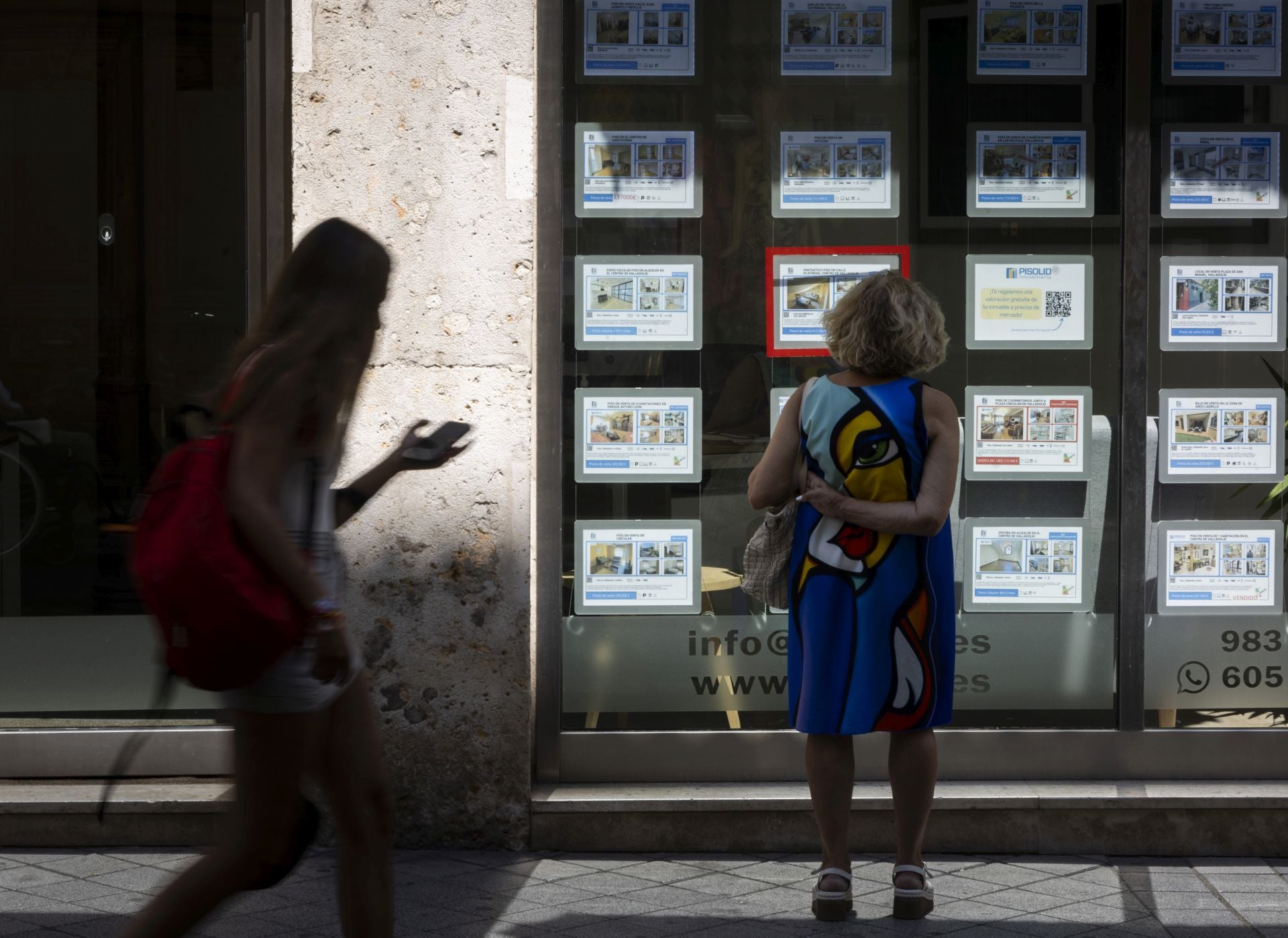 Una mujer consulta anuncios de viviendas en una inmobiliaria.