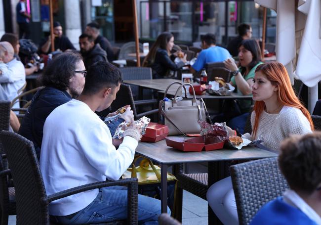 Tres de los cien 'afortunados' degustan su hamburguesa gratuita en la terraza