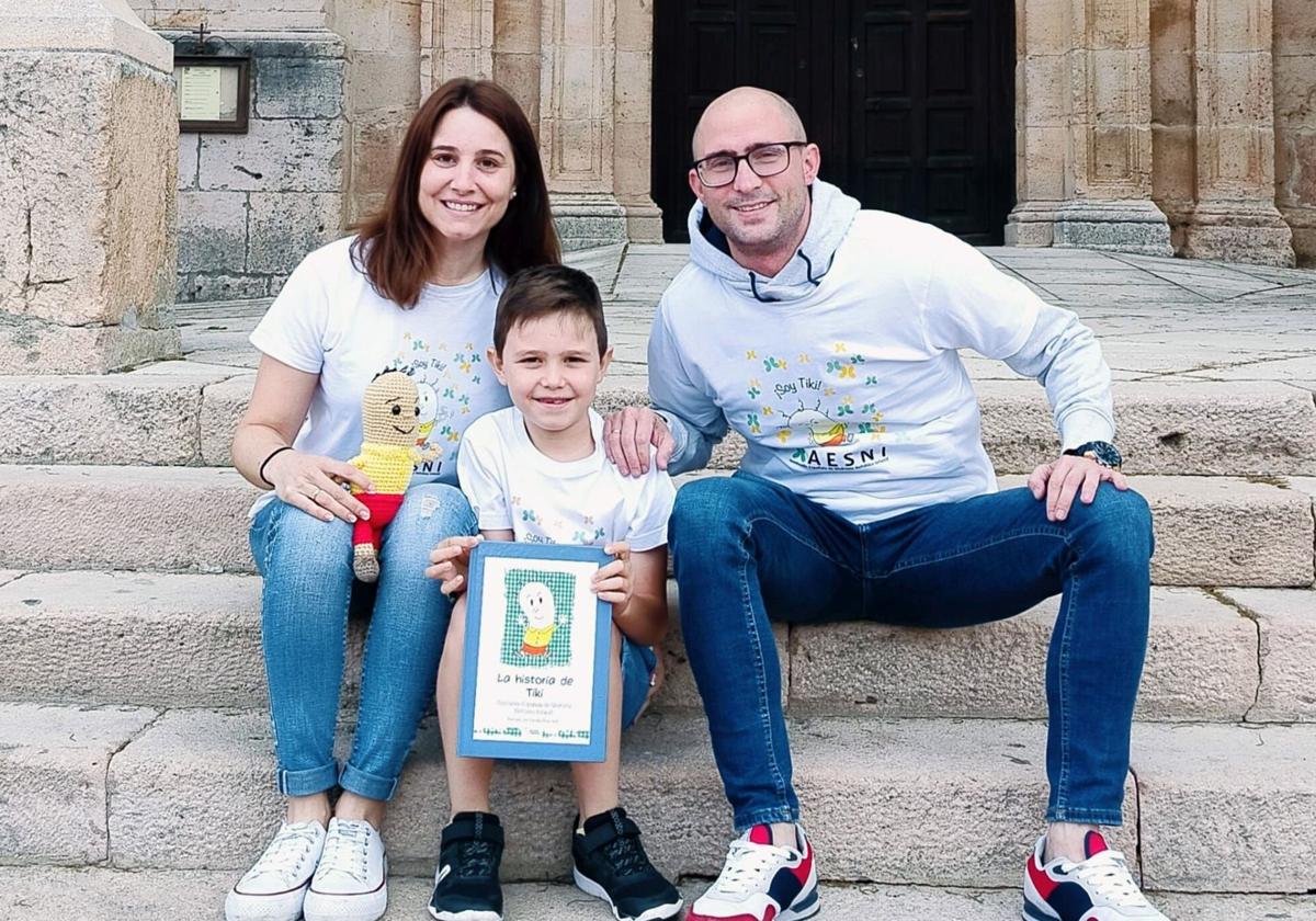 Manuel, junto a sus padres, sujeta un libro que divulga su enfermedad.