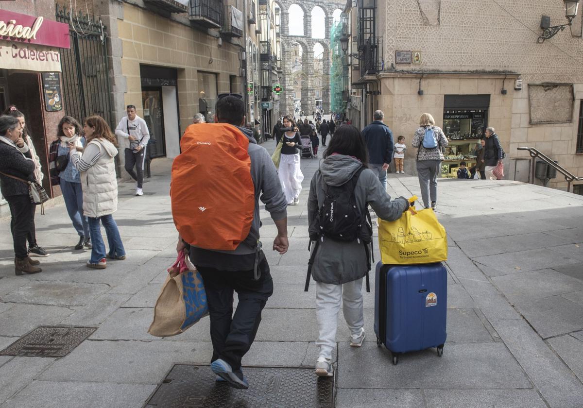 Dos personas caminan con maletas por la Calle Real este jueves.