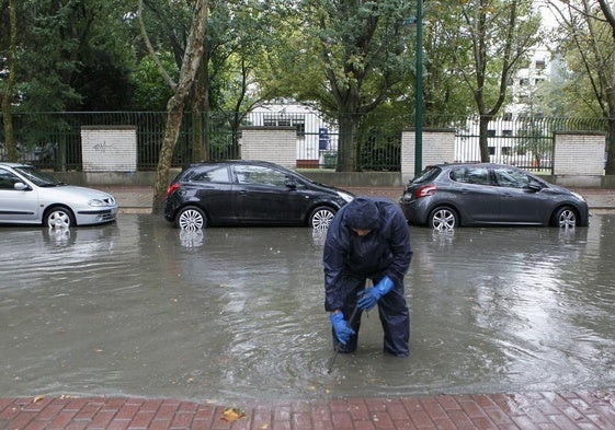 Trabajos para desatascar una alcantarilla, en una inundación tras una tromba de agua, en Prado de la Magdalena.