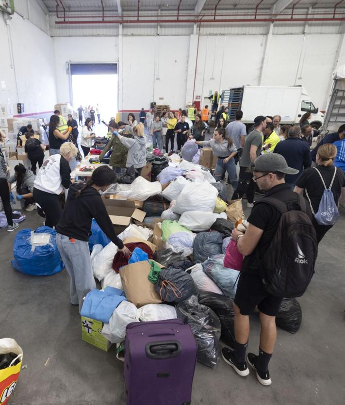 Imagen secundaria 2 - Palés preparados para enviar a Valencia y voluntarios, este martes en la nave habilitada en el polígono de San Cristóbal.