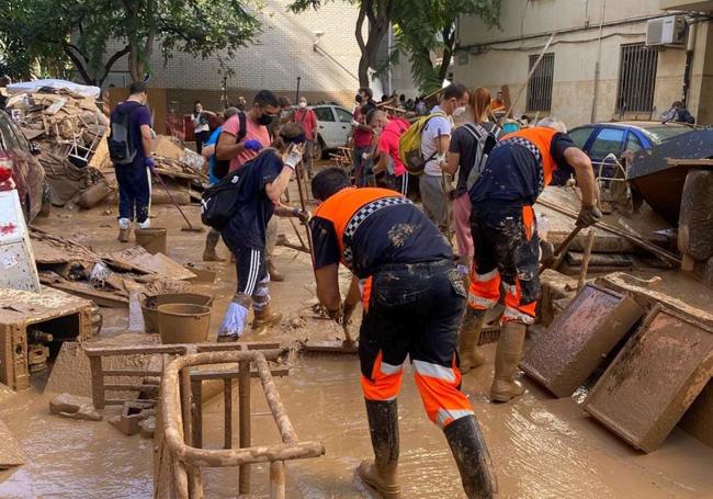 Integrantes de la Agrupación de Voluntarios de Protección Civil de Riaza retiran enseres inservibles y limpian una calle embarrada.