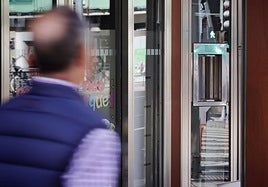 Un viandante pasa delante de una farmacias con el torno instalado para dispensar los fármacos durante las guardias.