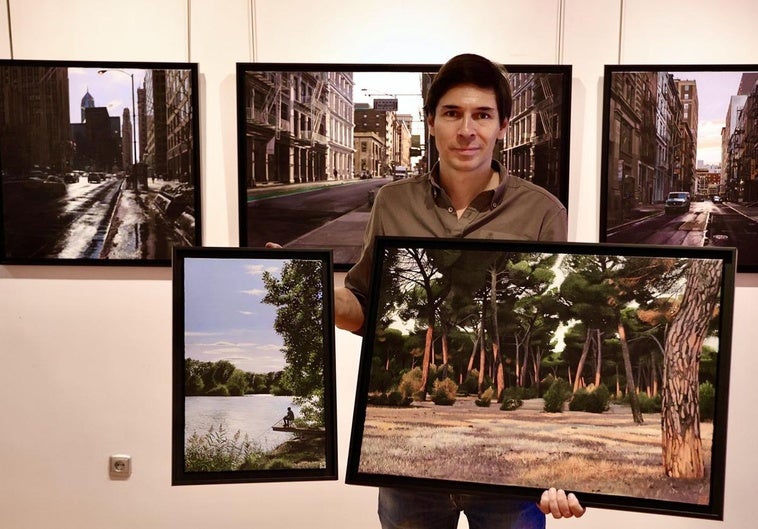 Luis Pérez con dos lienzos del río Pisuerga en San Miguel del Pino y del pinar de Simancas y, tras él, cuadros con paisajes urbanos de Chicago y Nueva York.