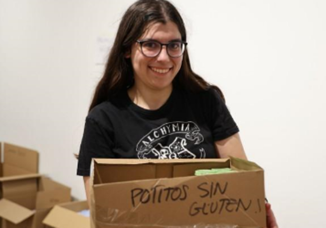 La voluntaria Ariadna Pena carga con una caja de potitos sin gluten.