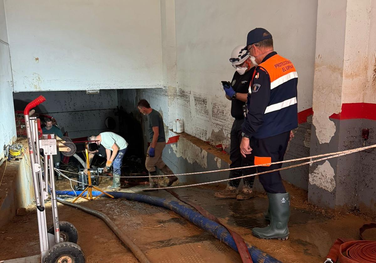 Miembros de Protección Civil El Espinar vacían de agua un garaje.