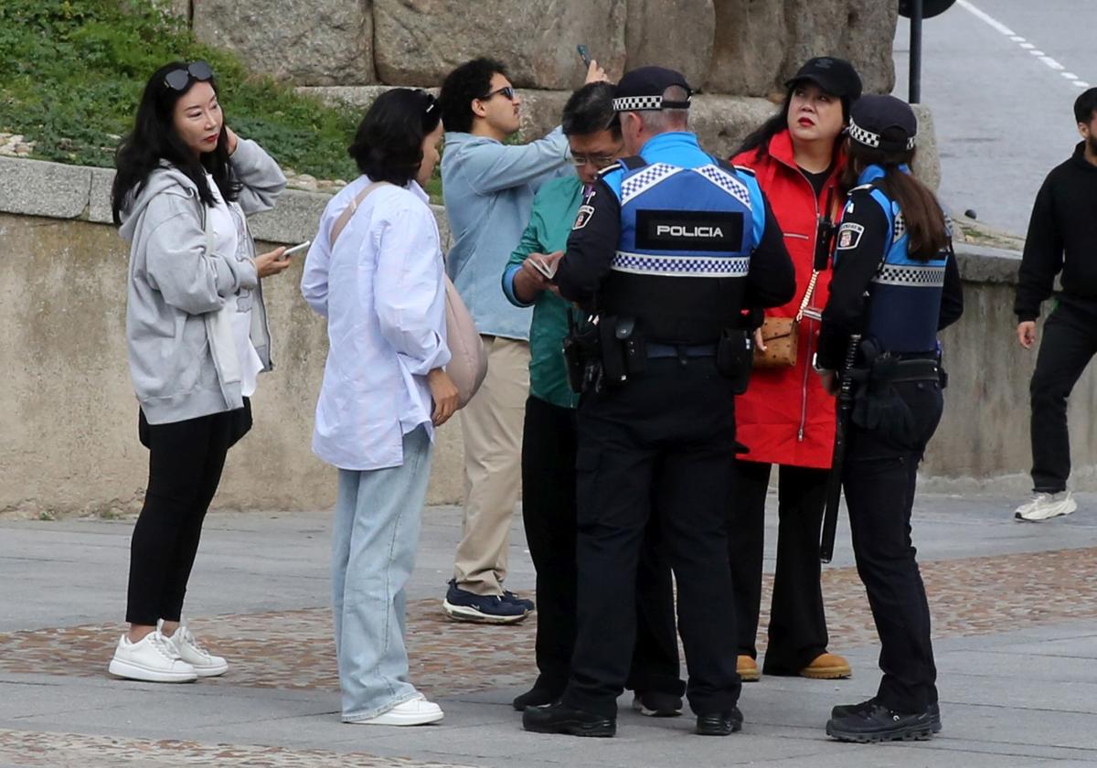 Agentes de la Policía Local atienden a turistas que han sufrido un robo en la plaza del Azoguejo.