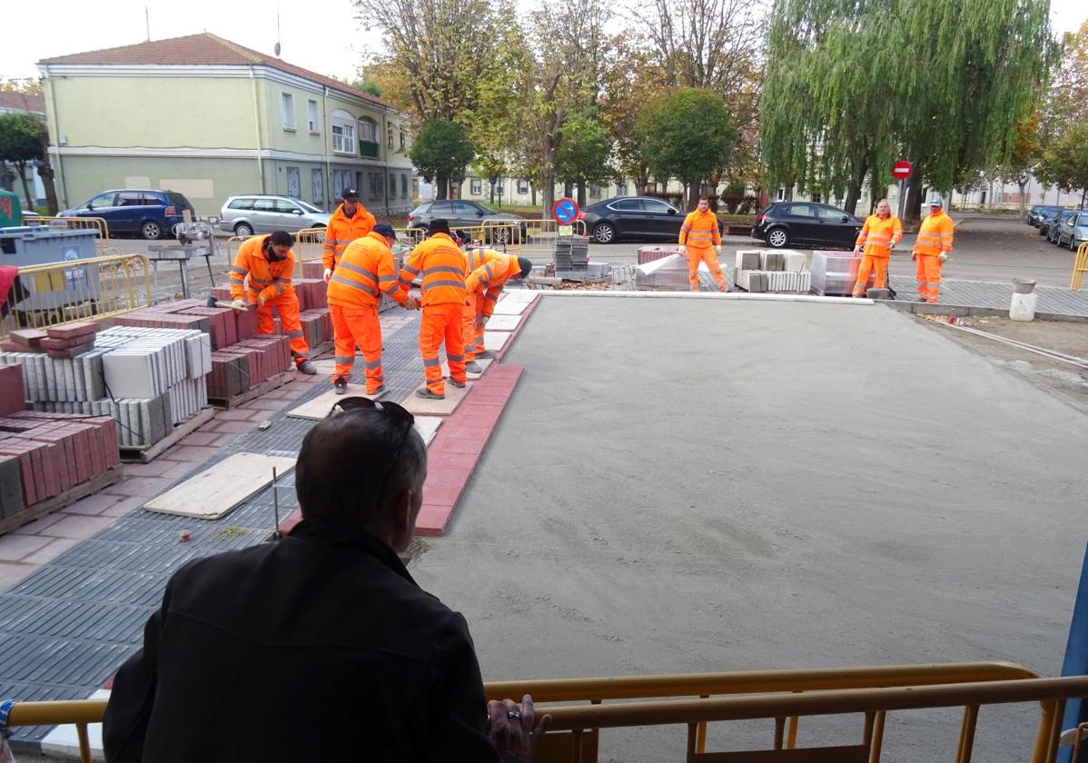 Un hombre observa los trabajos de urbanización de la plaza del Marqués de Suances desde la terraza del bar que ocupa su espacio central.