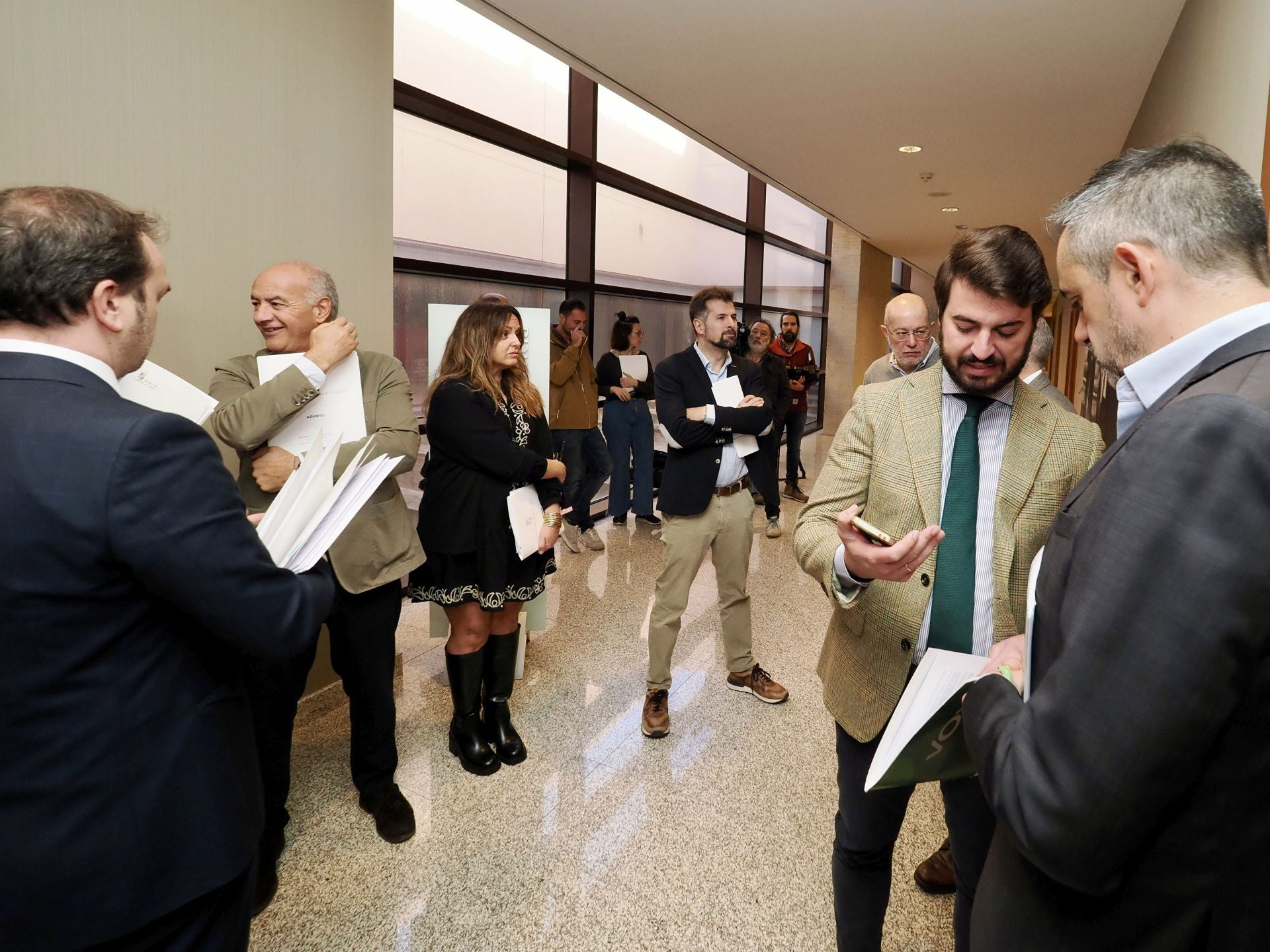 Portavoces parlamentarios esperan en uno de los pasillos de las Cortes de Castilla y León para entrar a una reunión.