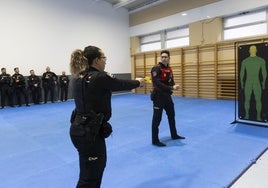 Una policía acciona la Taser ante la atenta mirada del instructor del curso.