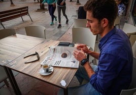 Una persona ojea un periódico en un bar.