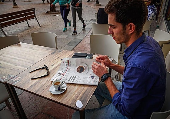 Una persona ojea un periódico en un bar.