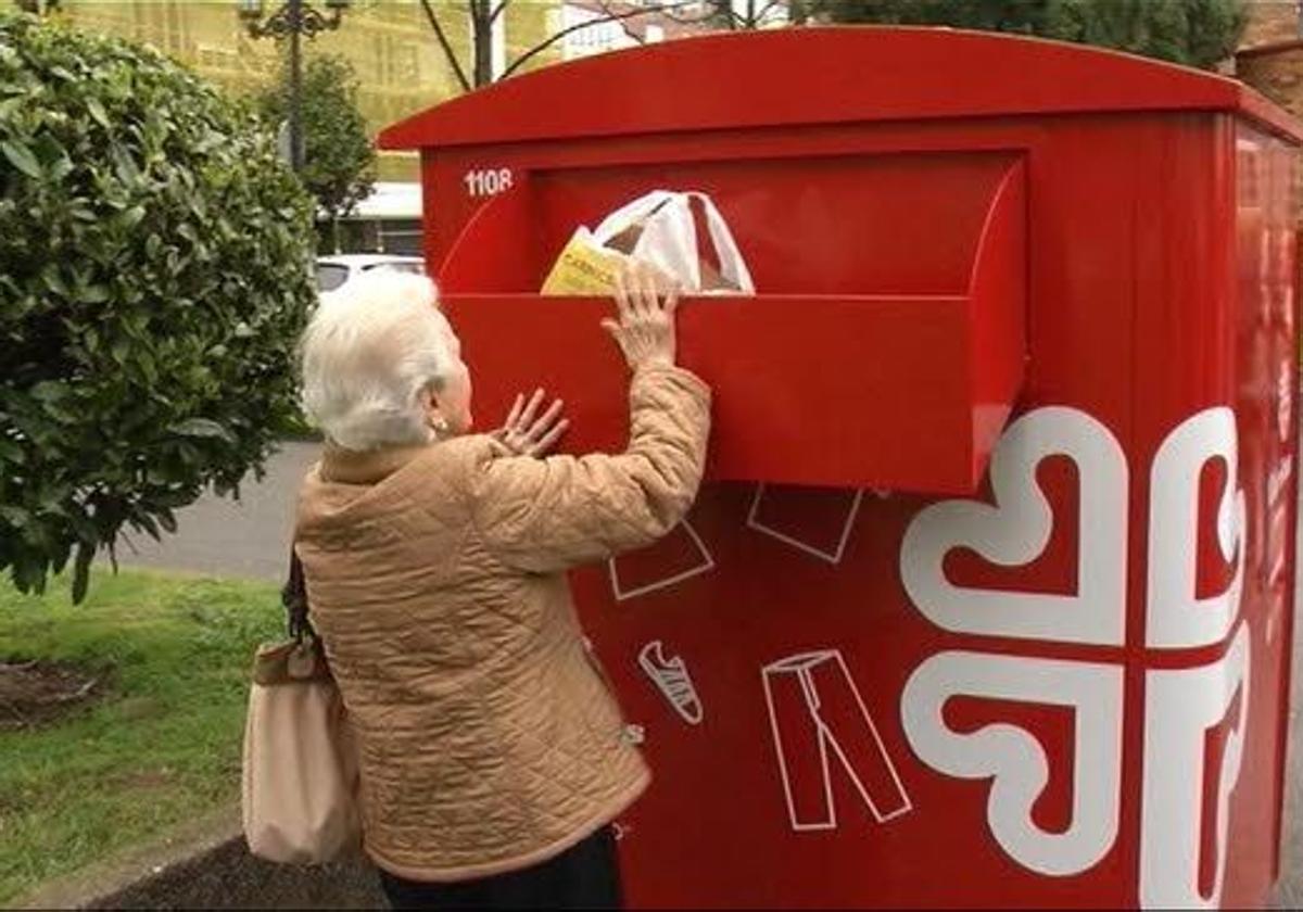 Una mujer deposita una bolsa con ropa en un contenedor de Cáritas.