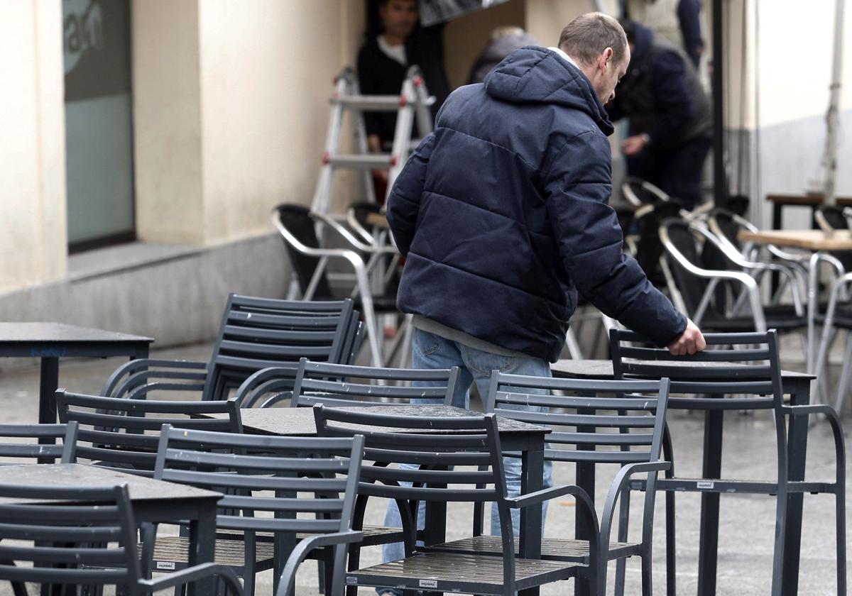 Un trabajador prepara una terraza en una céntrica calle de Segovia.