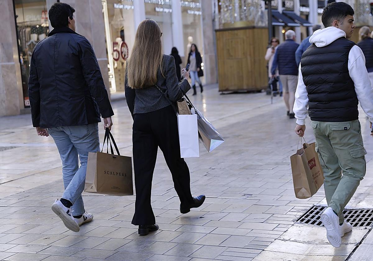 Unos jóvenes, con bolsas tras realizar unas compras en la campaña navideña.