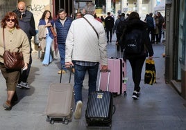 Visitantes con maletas pasean por el centro de Segovia este jueves.