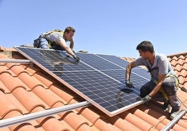 Dos instaladores colocan paneles solares en un tejado.