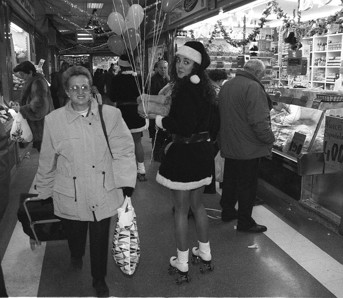 Una joven vestida de Papá Noel reparte globos a los niños en el mercado de El Campillo. 23 de diciembre de 1998.