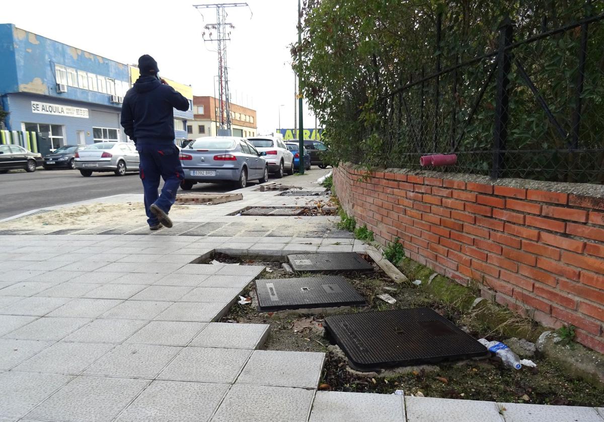 Un trabajador camina por el cruce de la avenida de El Norte de Castilla con Forja entre registros sin rematar, arena y agujeros cubiertos con palés.