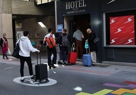 Viajeros entran al hotel Alda, en la calle Eduardo Dato, el pasado puente de Los Santos.