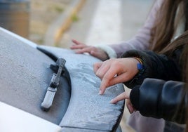 Jóvenes realizan dibujos en el hielo que cubre un coche en la provincia de Segovia.