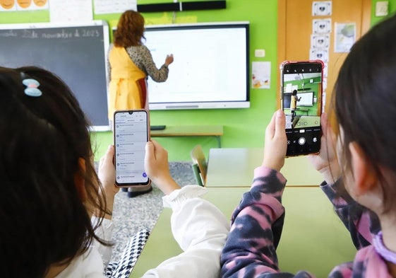 Dos alumnas utilizan el teléfono móvil en un aula en Castilla y León.