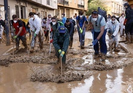 Un grupo de jóvenes voluntarios retira el barro de una calle de Paiporta.