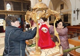 Varias cofrades visten al Niño de la Bola para la procesión.