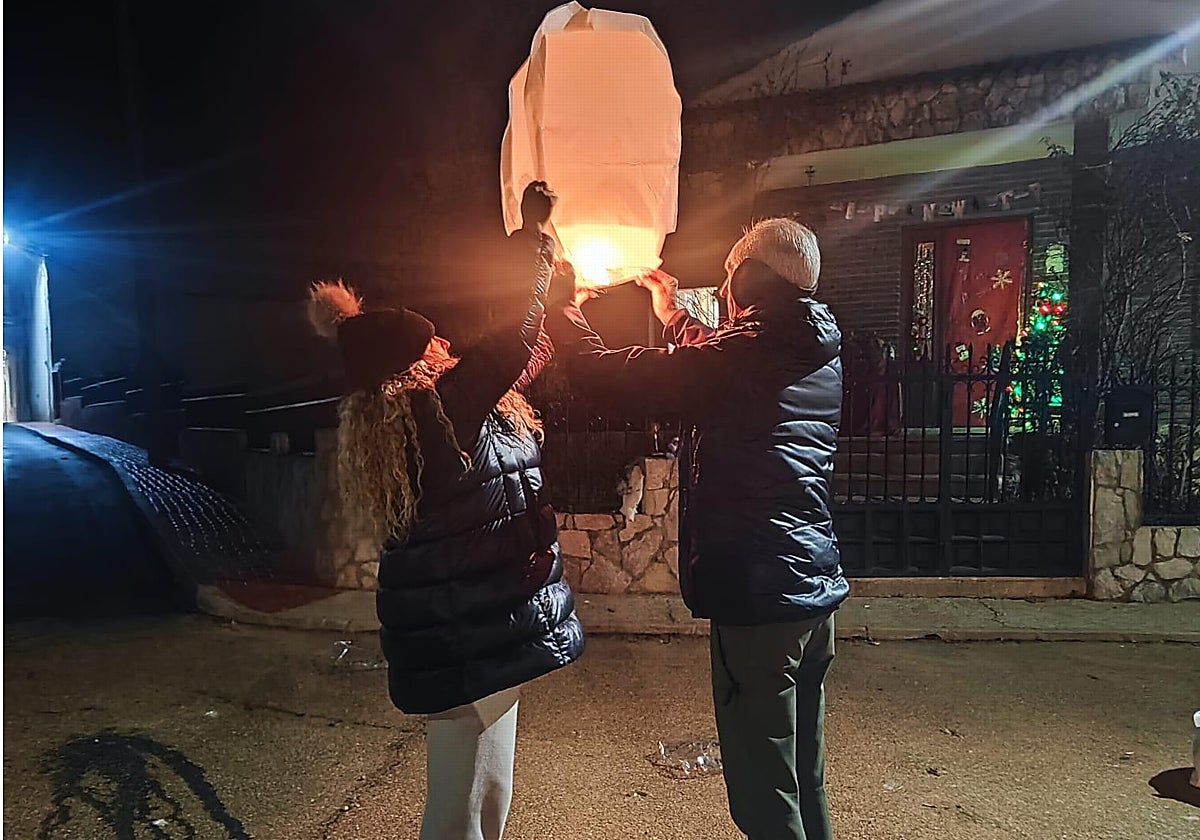 Dos vecinos hacen volar uno de los farolillos de la suerte para recibir el 2025