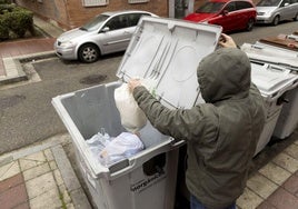 Un hombre deposita una bolsa de basura en un contenedor.