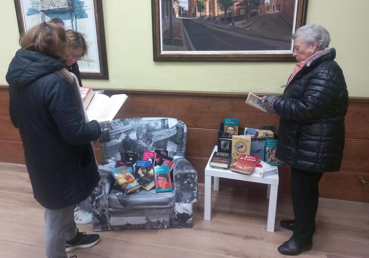 Tres vecinas de La Seca eligen libros para regalar dentro de la actividad 'Ajuntaletras'.