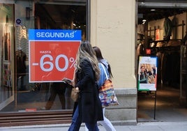 Dos mujeres pasan junto a un cartel de rebajas en la Calle Real.