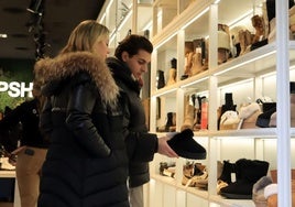 Dos clientes observan productos en una tienda de calzado de Segovia.