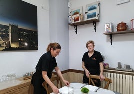 Mari Mar Infante y Pilar Fombellida colocan una mesa de su restaurante de Baltanás.