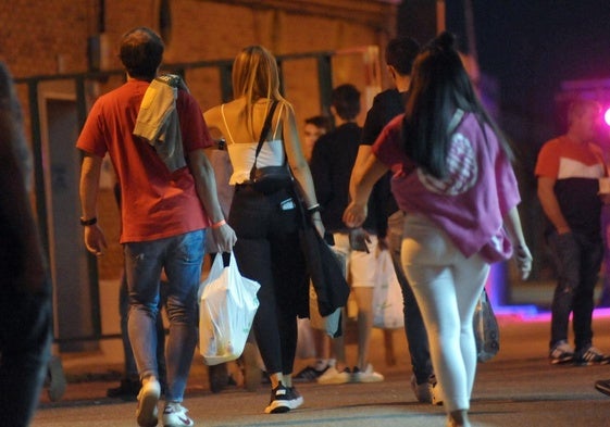 Unos jóvenes portan bolsas con bebidas alcohólicas, en una imagen de archivo.