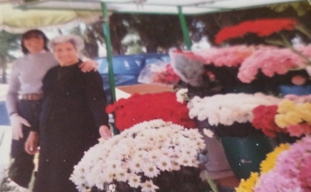 Lidia Alonso junto a su madre hace 35 años en el puesto de flores del Cementerio del Carmen.