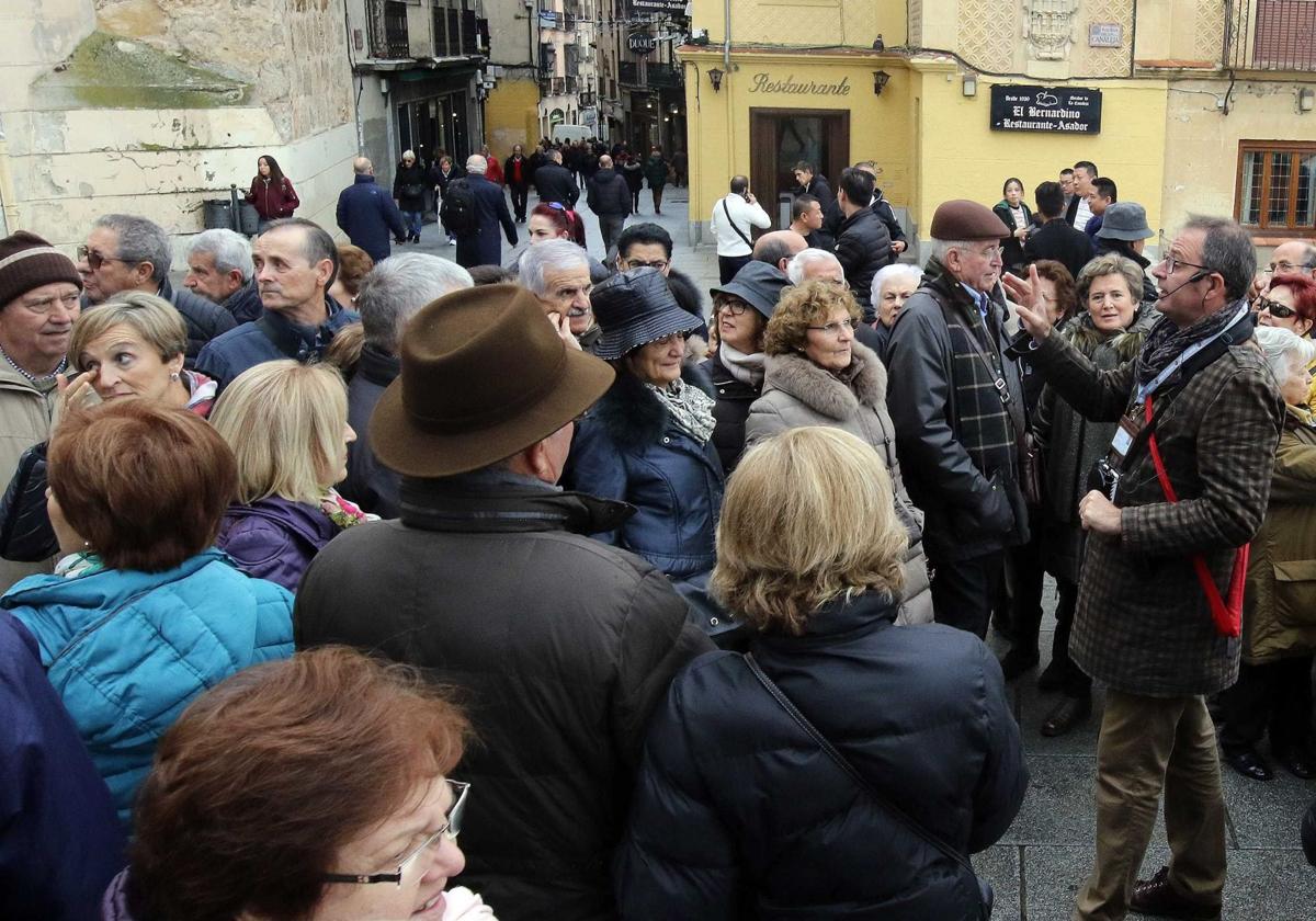 Un guía oficial habla del teatro Cervantes a un grupo de turistas, en la Calle Real de Segovia.