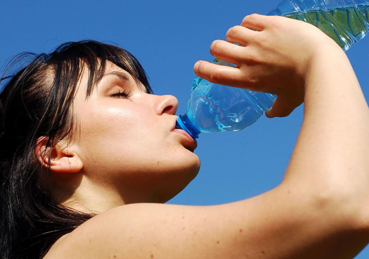 Una joven se hidrata bebiendo agua.