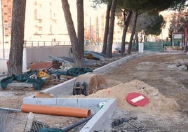 Zona de aparcamiento, delimitada por los bordillos, junto a los pinos situados junto al muro del túnel de Labradores.